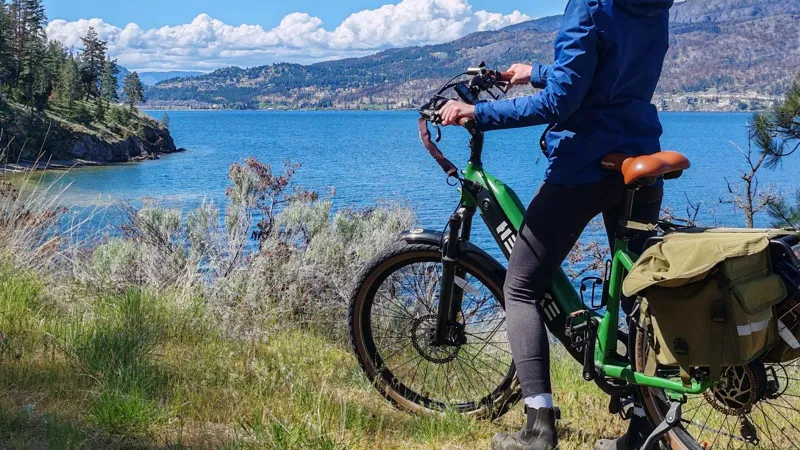 Rider on a rented e-bike with panniers above Okanagan Lake on a self-planned Kelowna bicycle wine tour route